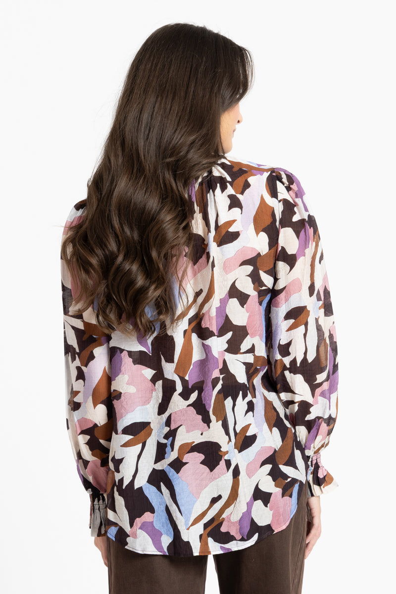 Woman wearing a patterned blouse with a white background