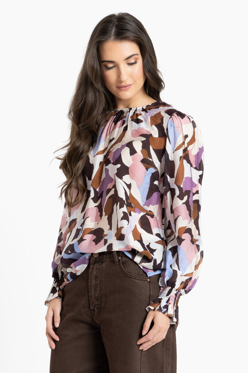 Woman wearing a patterned blouse with long sleeves on a white background