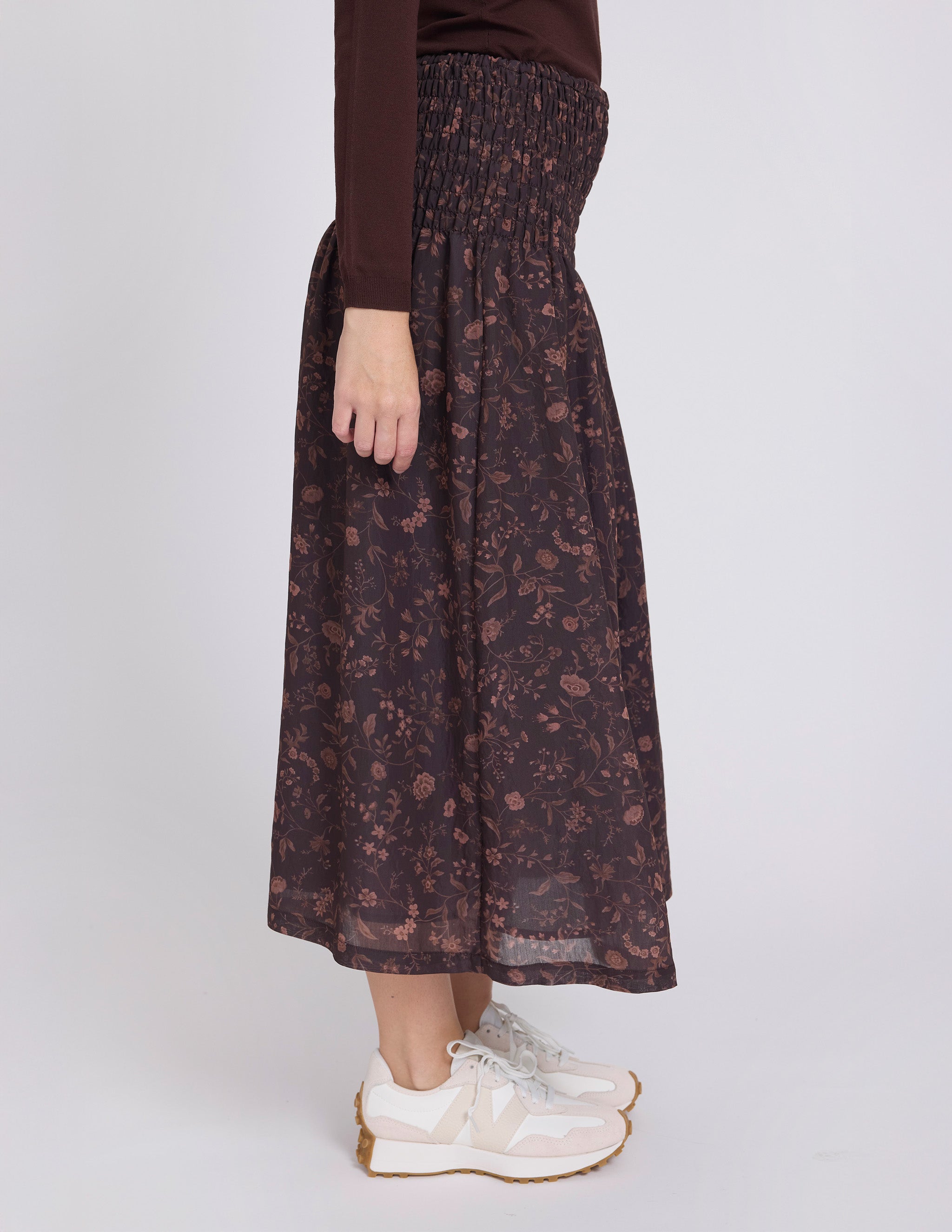 Person wearing a dark floral skirt on a white background