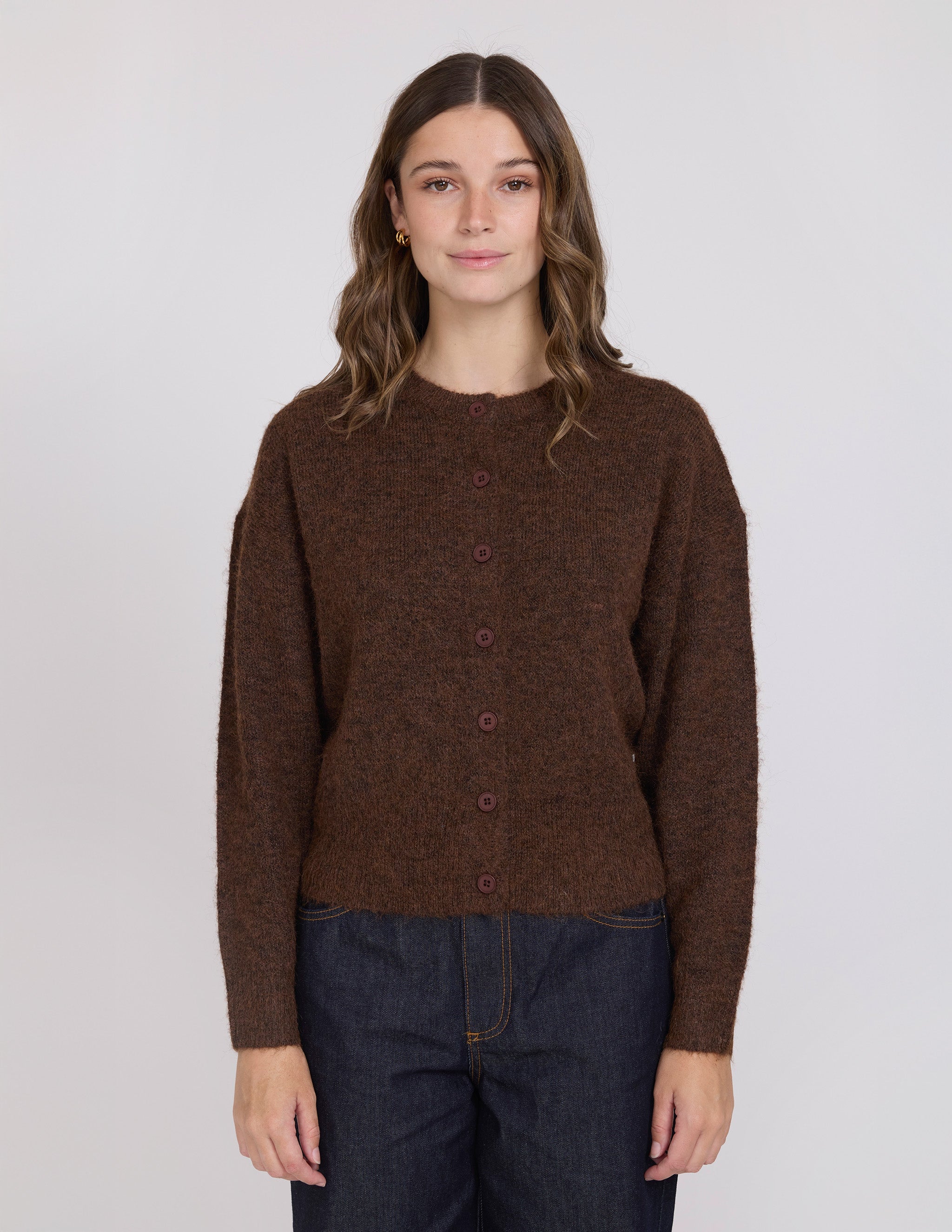Woman wearing a brown button-up sweater against a white background