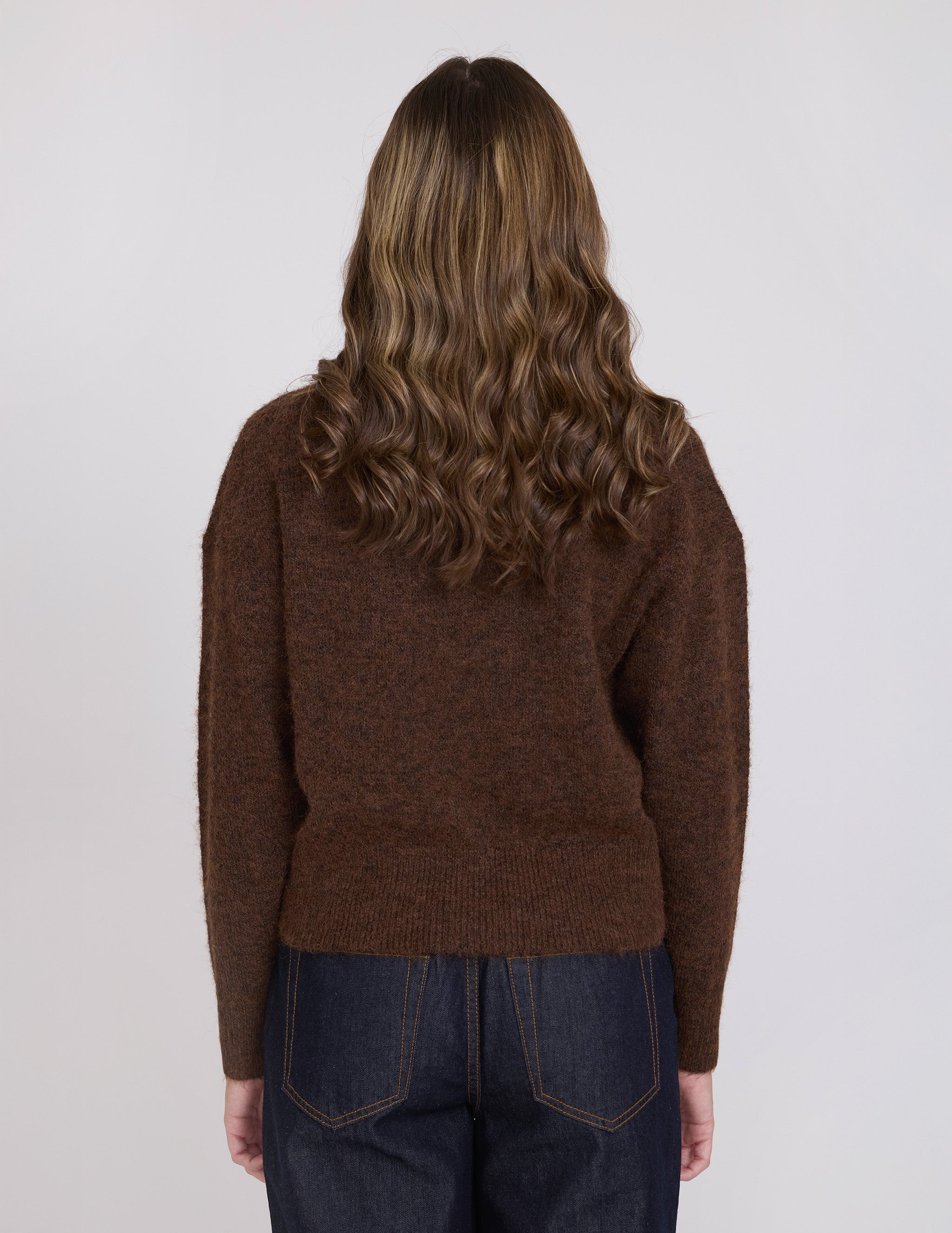 Person wearing a brown sweater from behind on a white background