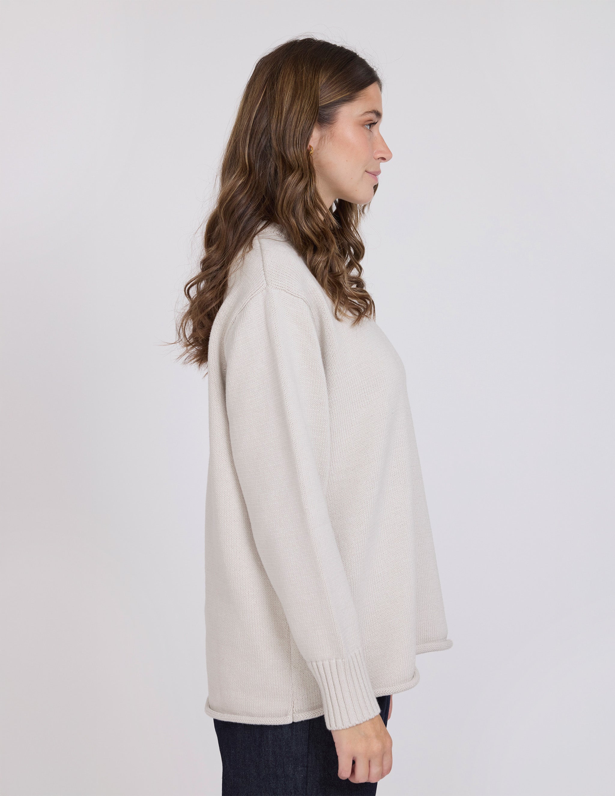 Woman wearing a beige sweater against a white background
