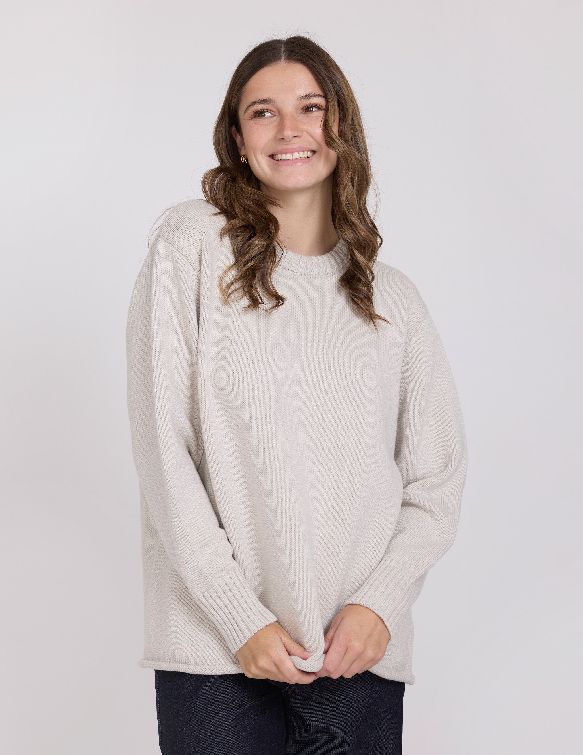 Woman wearing a light beige sweater against a white background