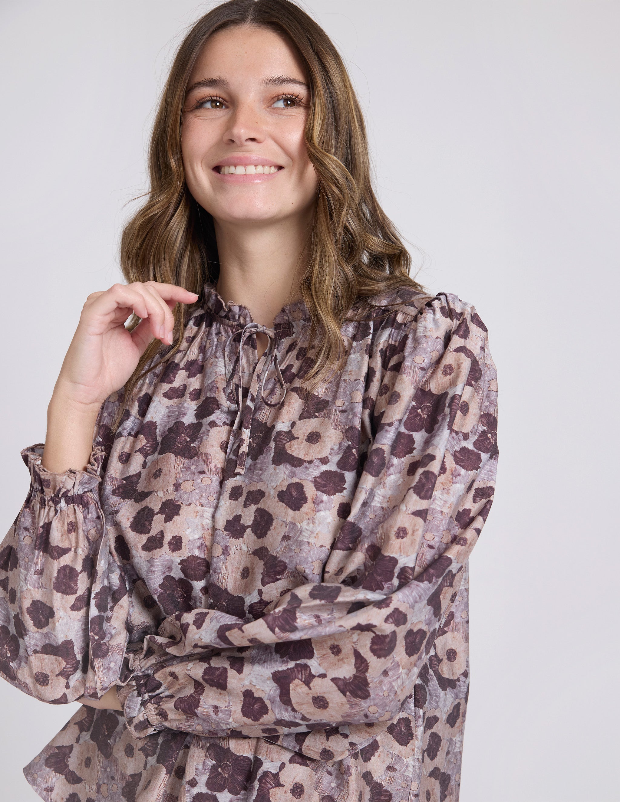 Woman wearing a floral blouse against a plain background