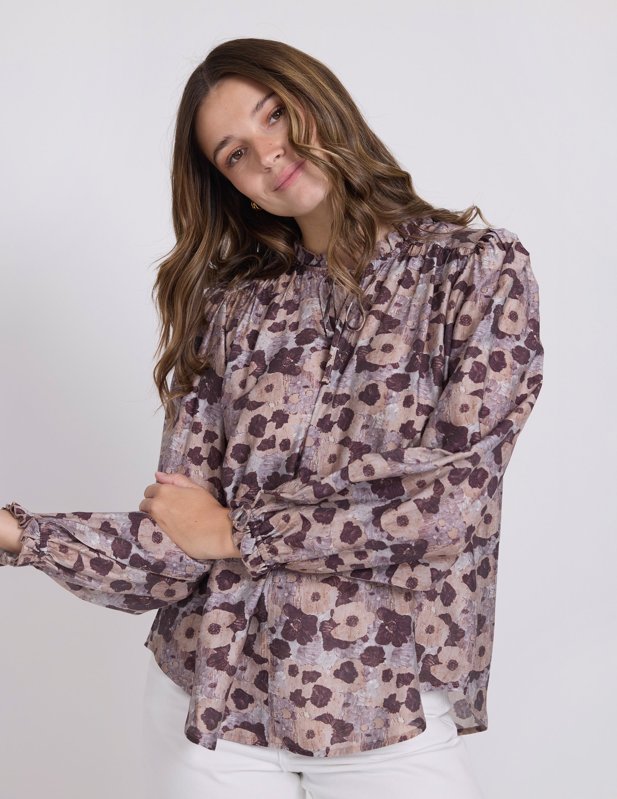 Woman wearing a floral patterned blouse against a white background
