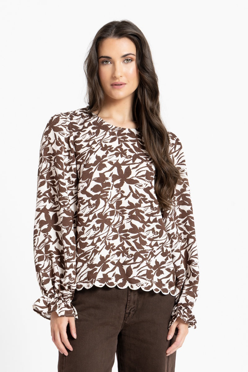 Woman wearing a brown and beige floral blouse against a white background
