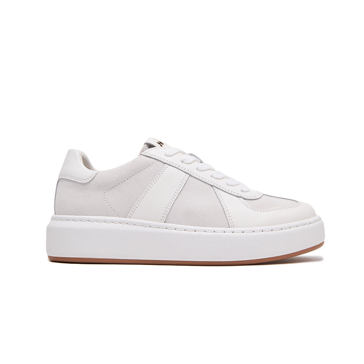 A low-top platform sneaker in white and light gray suede and leather, featuring a thick white sole and a gum brown outsole, shown from a side profile on a white background.