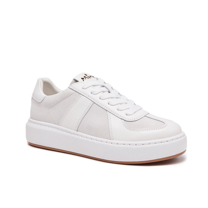 A white low-top platform sneaker with white laces, white leather and suede panels, and a light brown gum outsole, shown from a three-quarters angle on a white background.