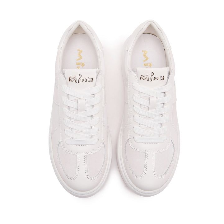 A pair of white low-top sneakers shown from a top-down view on a solid white background. The shoes feature white laces, white leather panels, and a white rubber sole, with the brand name 'Minn' printed in gold on the tongue and gold logo on the insole.