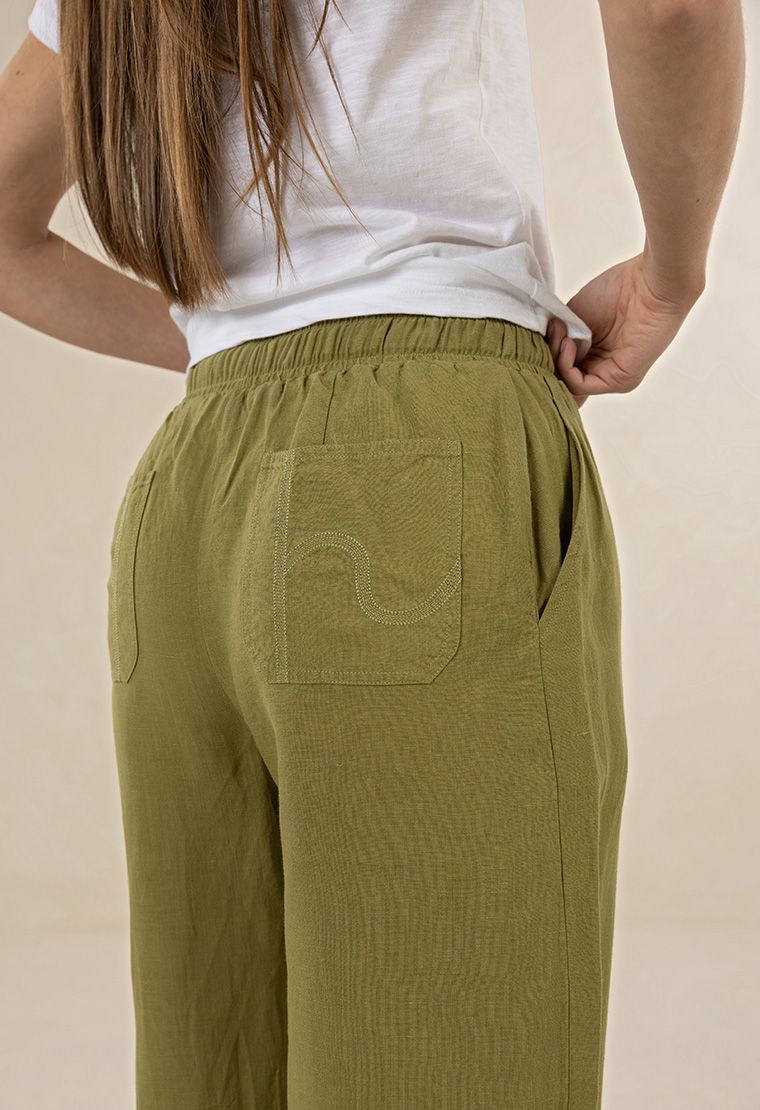 Person wearing green pants with a pocket detail on a beige background