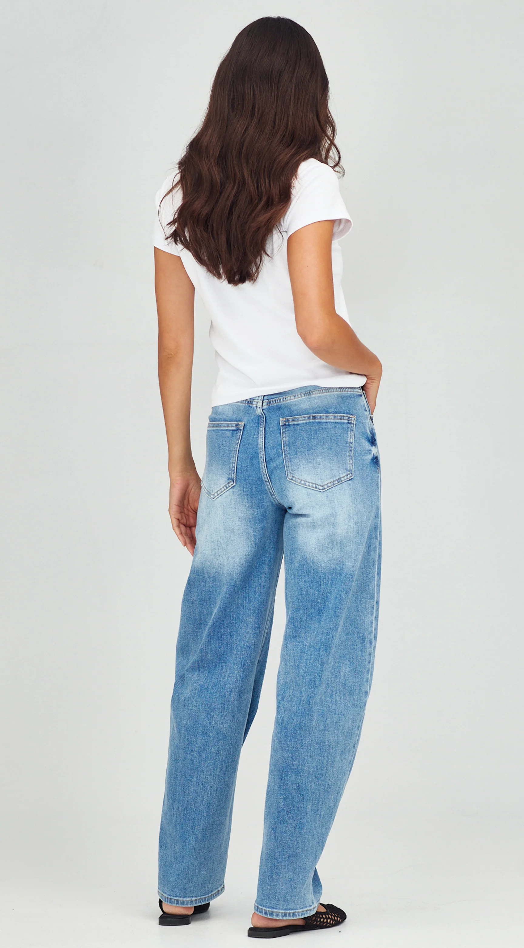 Person wearing light blue jeans and a white t-shirt on a plain background