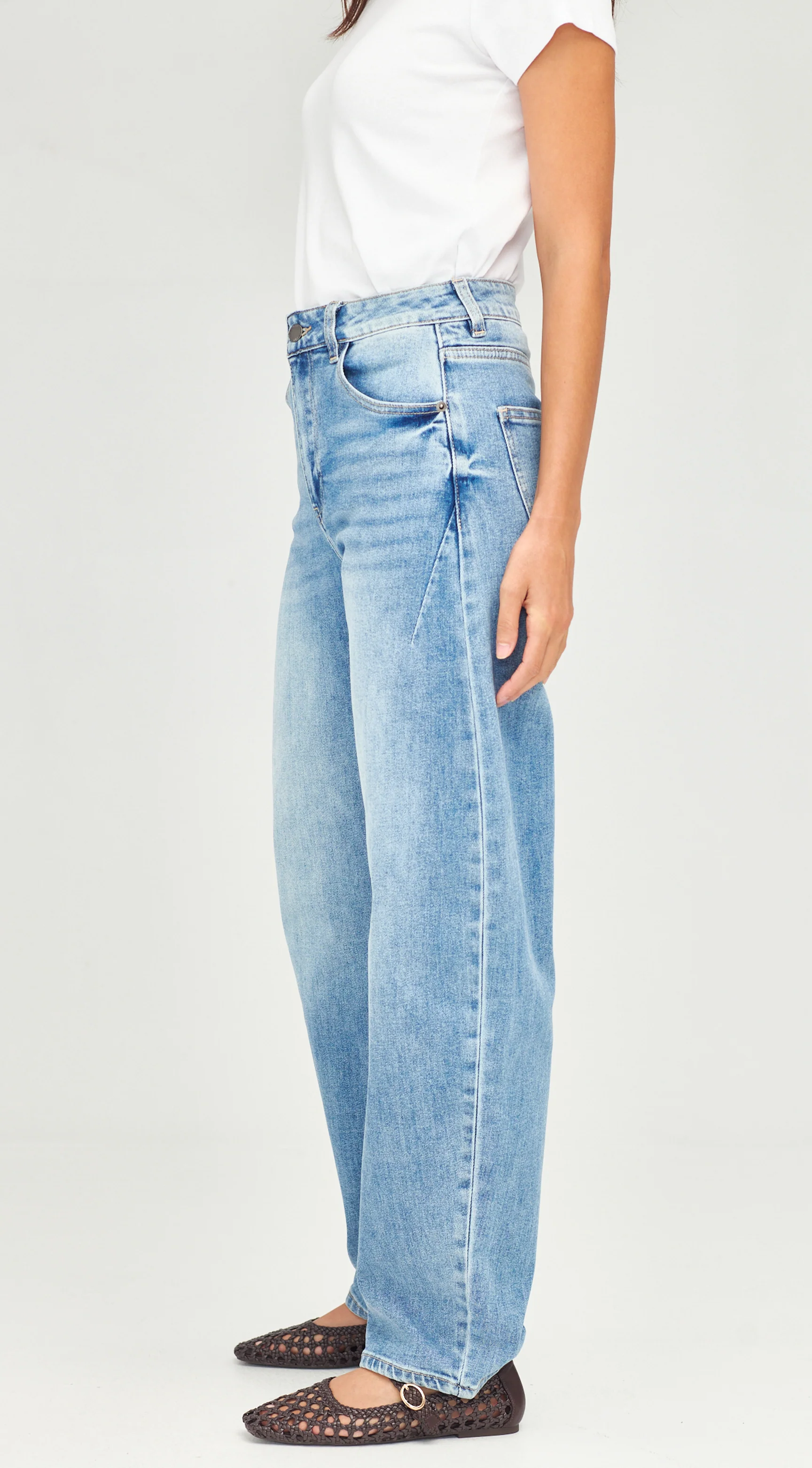 Person wearing light blue jeans and a white shirt on a plain background