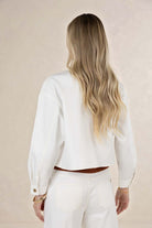 Person wearing a white shirt and pants against a beige background