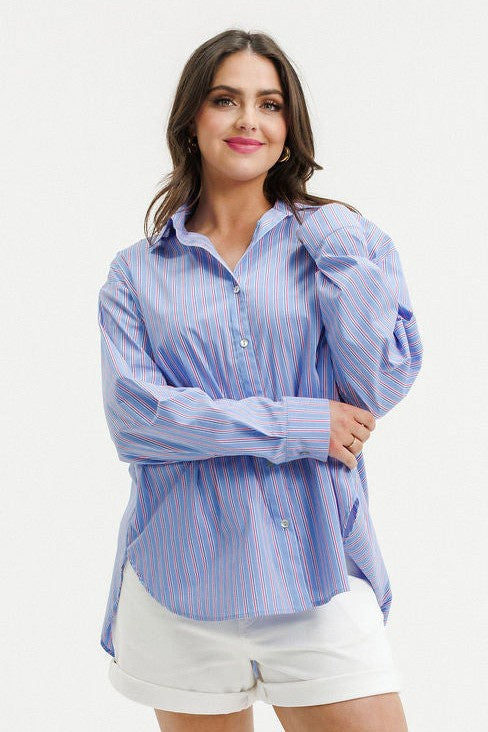 A woman wearing a light blue and white vertically striped button-up shirt with puffed sleeves, paired with white shorts, against a plain white background.