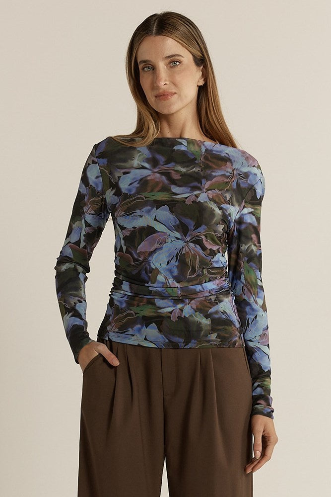 Woman wearing a long-sleeve floral top and brown pants on a beige background