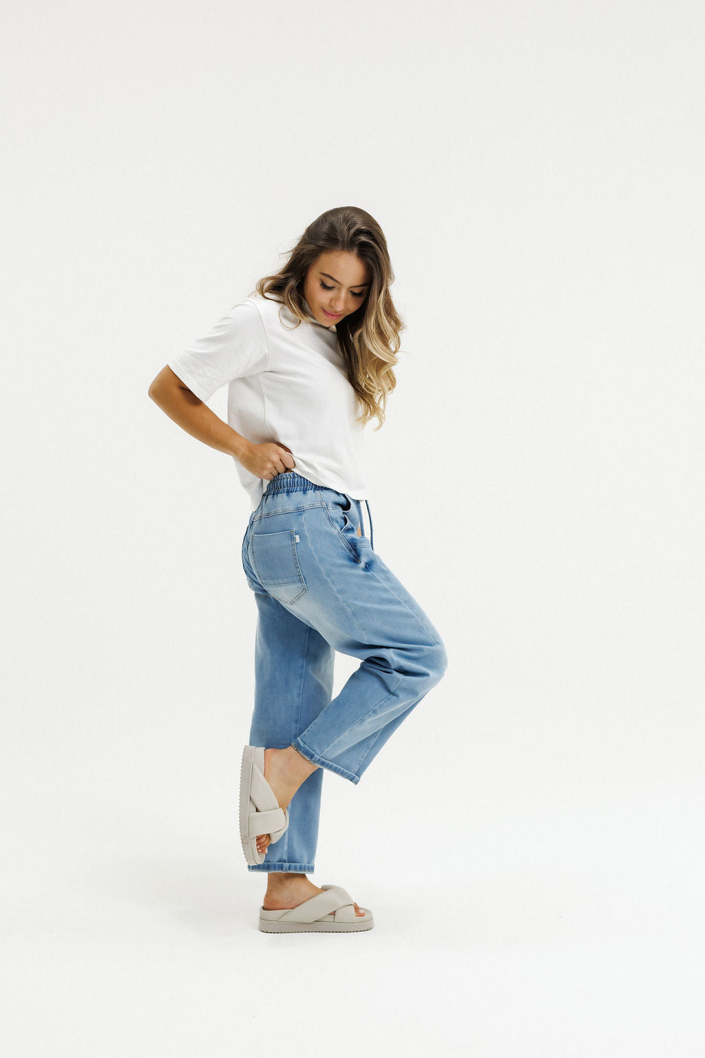 Woman wearing a white shirt and blue jeans on a white background