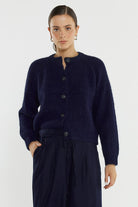Woman wearing a navy blue cardigan and pants on a white background