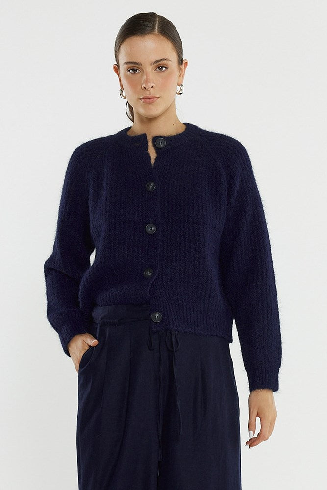 Woman wearing a navy blue cardigan and pants on a white background