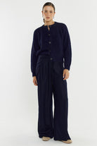 Person wearing a navy blue cardigan and pants on a white background