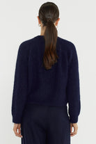 Person wearing a dark blue sweater against a white background
