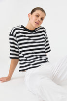 Person wearing a black and white striped sweater sitting on a white surface.
