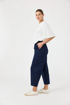 Woman wearing a white top and navy pants on a white background