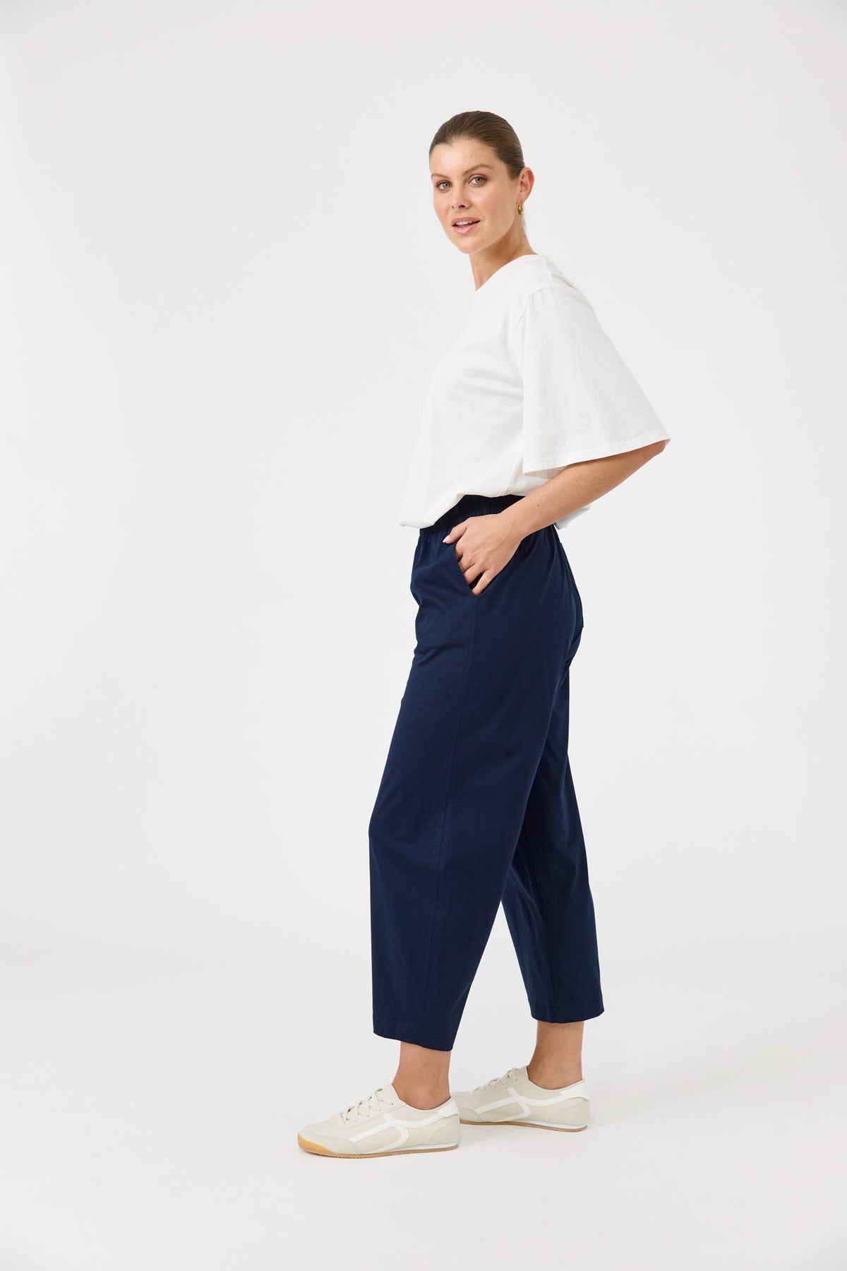 Woman wearing a white top and navy pants on a white background