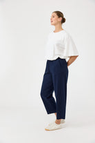 Woman wearing a white top and navy pants on a white background