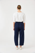 Person wearing a white top and navy pants on a white background