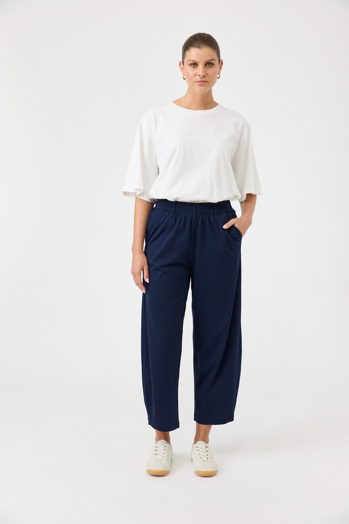Person wearing a white top and navy pants on a white background