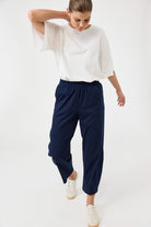 Woman wearing a white top and navy pants on a white background