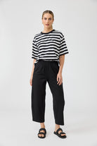 Woman wearing a black and white striped shirt and black pants on a white background