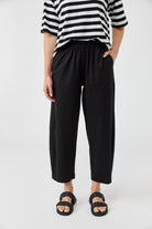 Person wearing a black and white striped shirt with black pants on a white background
