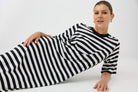 Person wearing a black and white striped dress on a plain background