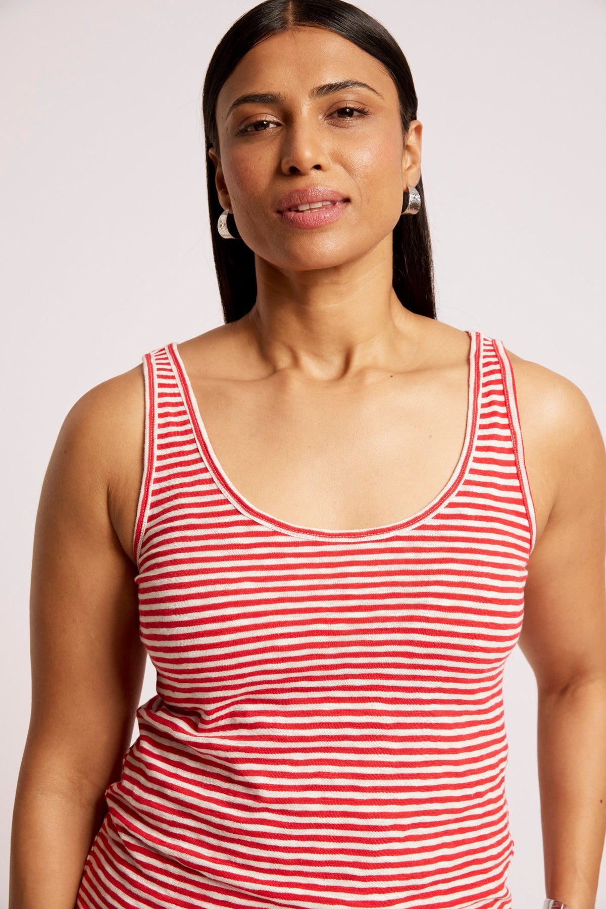 A woman wearing a red and white horizontally striped tank top, shown from the chest up against a plain light background.