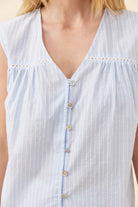 Close-up of a sleeveless light blue and white striped top with a V-neckline, button front, and eyelet trim.