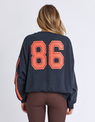 rear of woman wearing navy sweatshirt with orange writing