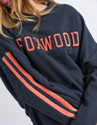 closeup of a woman wearing navy sweatshirt with orange writing