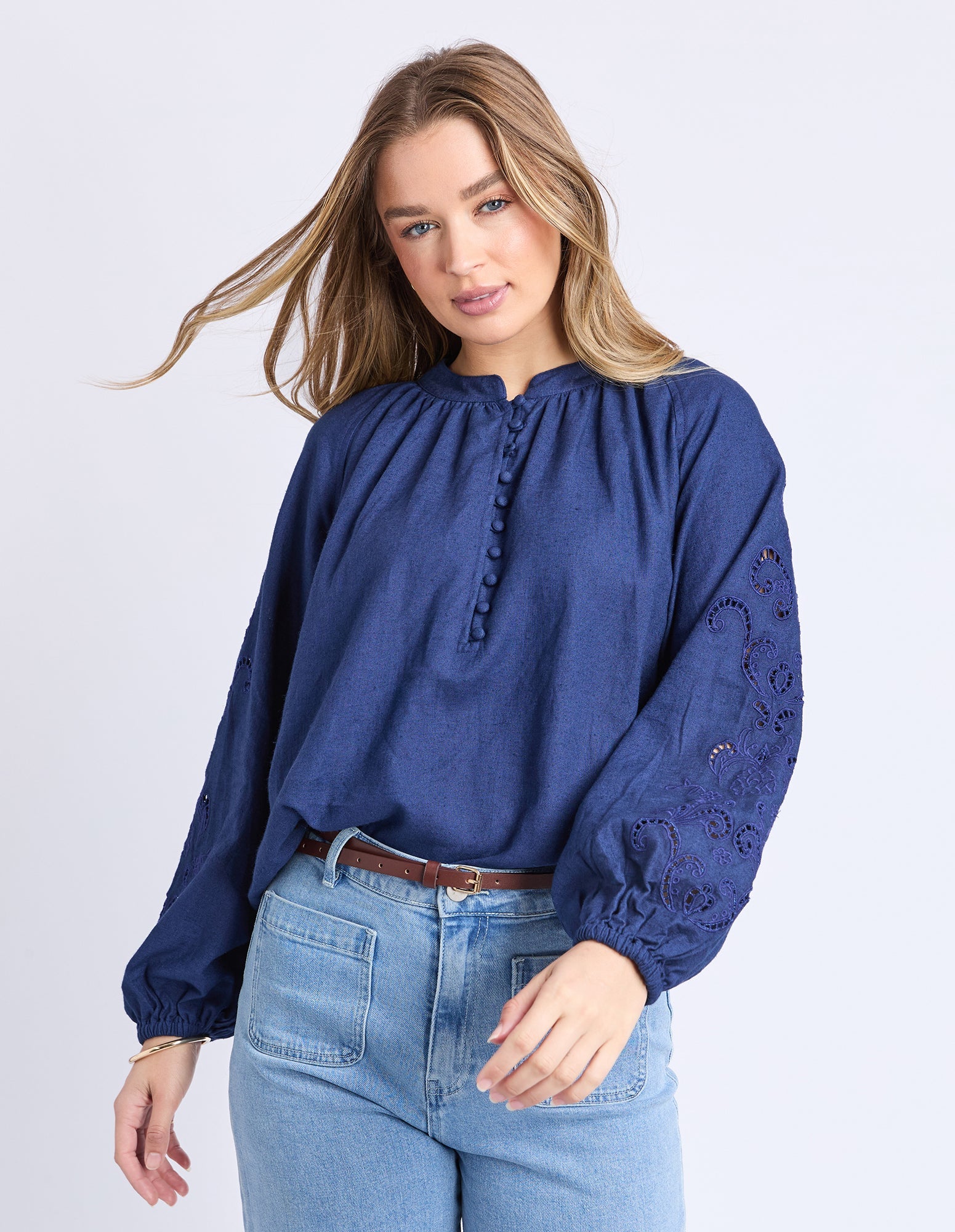 Woman wearing a blue blouse with lace sleeves against a white background