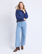 Woman wearing a blue shirt and light blue jeans on a white background