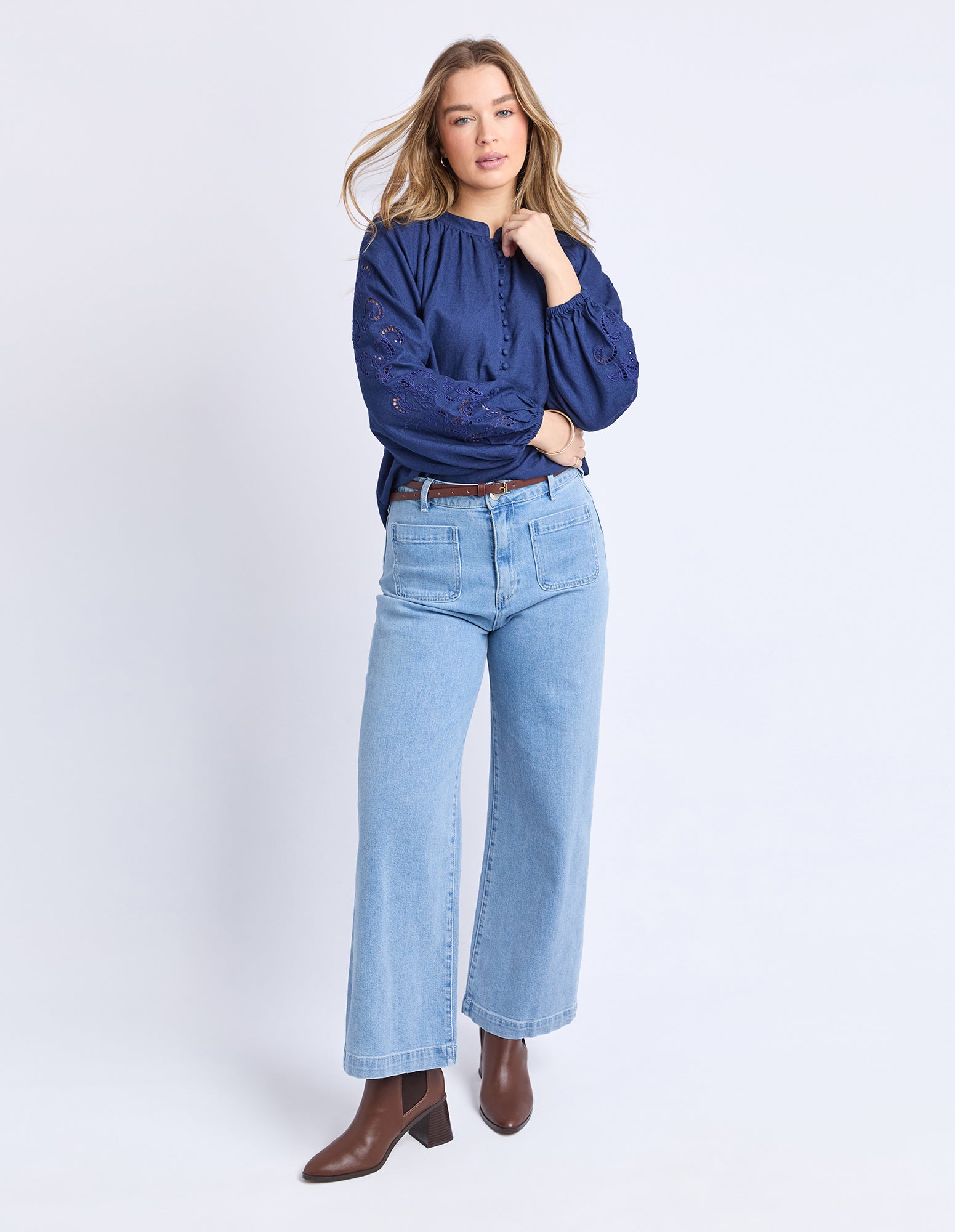 Woman wearing a blue shirt and light blue jeans on a white background