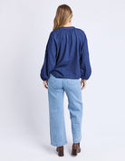 Person wearing a blue blouse and light blue jeans on a white background