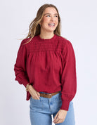 Woman wearing a red blouse and blue jeans on a white background