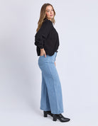 Woman wearing a black top and light blue jeans on a white background