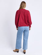 Person wearing a red blouse and blue jeans on a white background