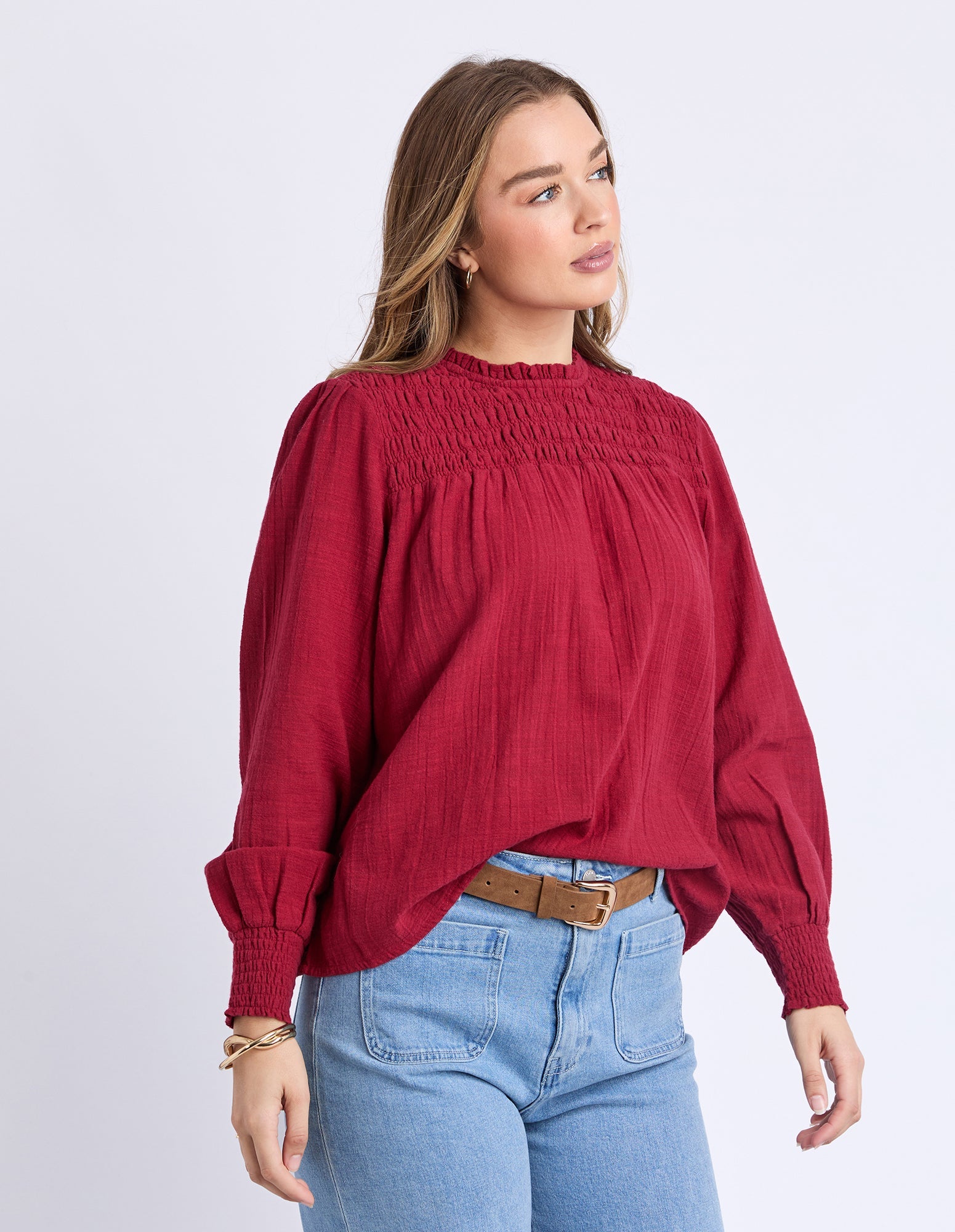 Woman wearing a red blouse and blue jeans on a white background
