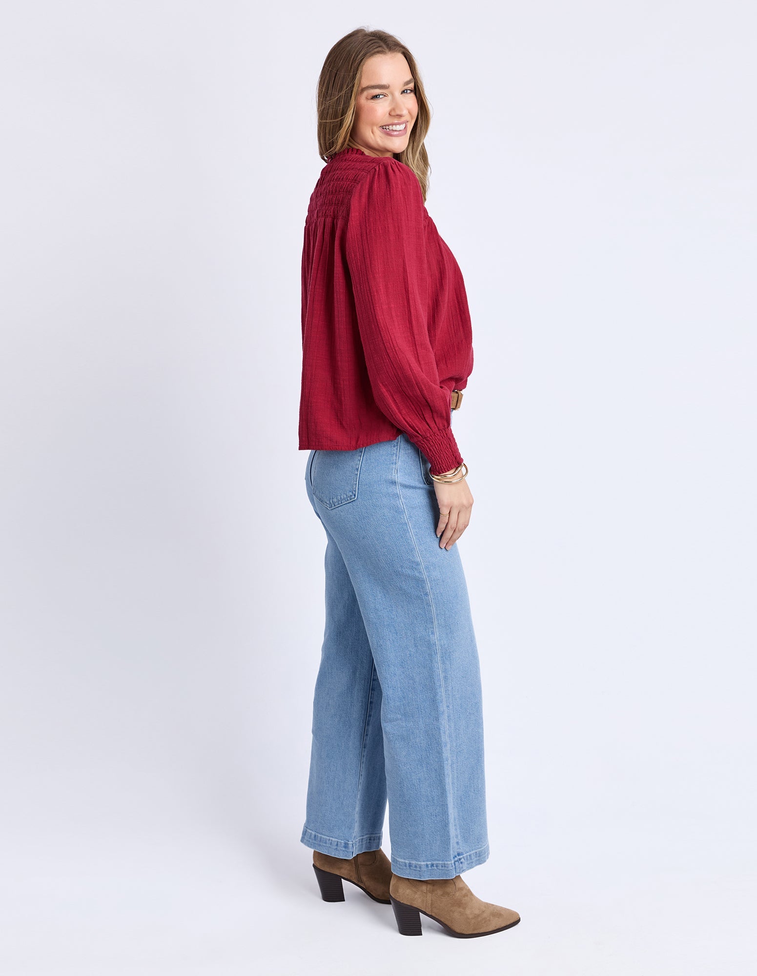 Woman wearing a red blouse and blue jeans on a white background