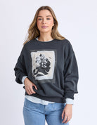 Woman wearing a dark gray sweatshirt with floral design on a light gray background