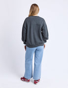 Person wearing a dark gray sweatshirt and light blue jeans on a white background