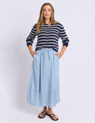 Woman wearing a striped sweater and light blue skirt on a white background